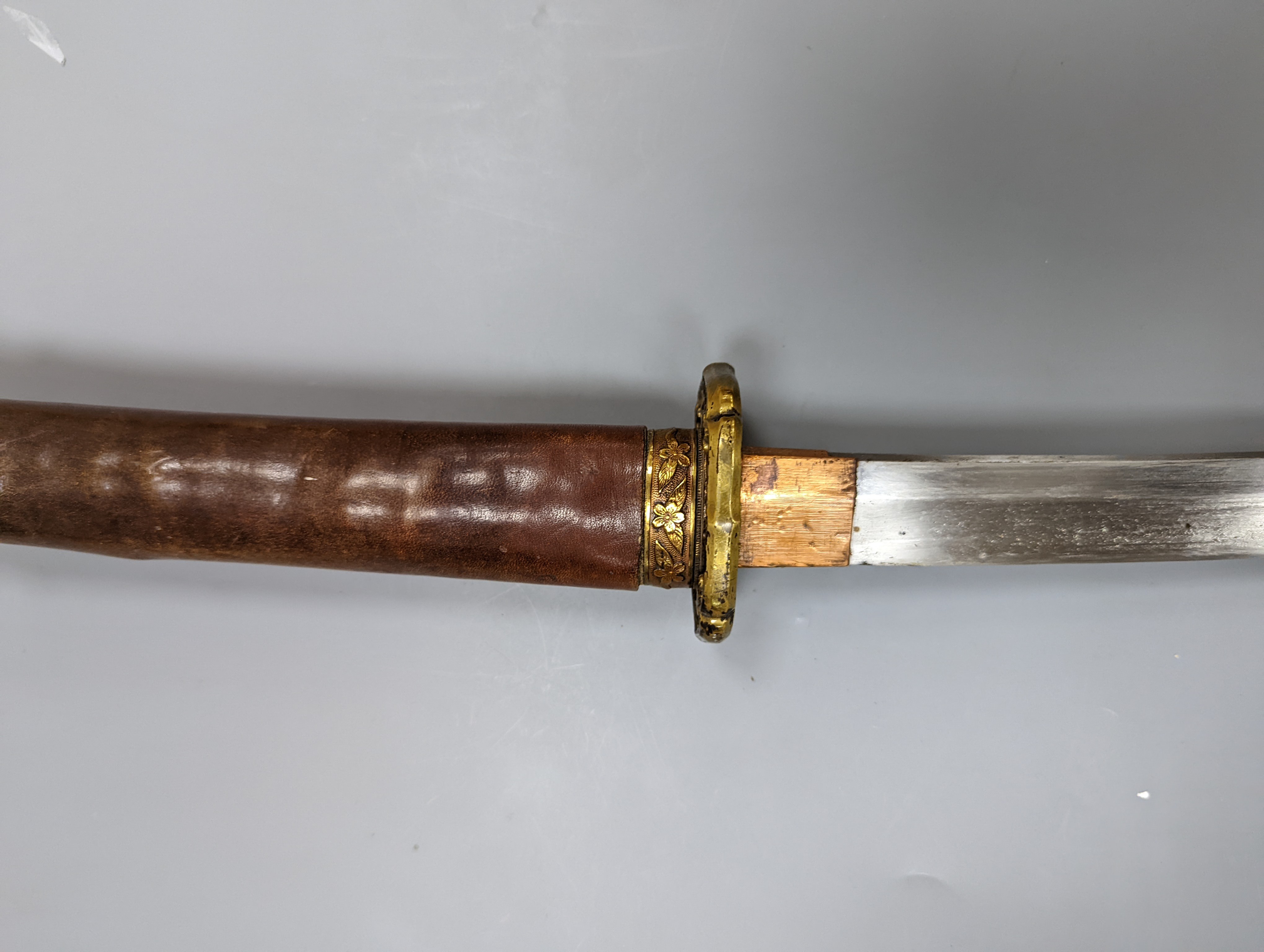 A Japanese Katana with leather covered sheath, plaque reading ‘Presented to Capt. S. Mear Telecoms B.M.A’ 93 cms long.